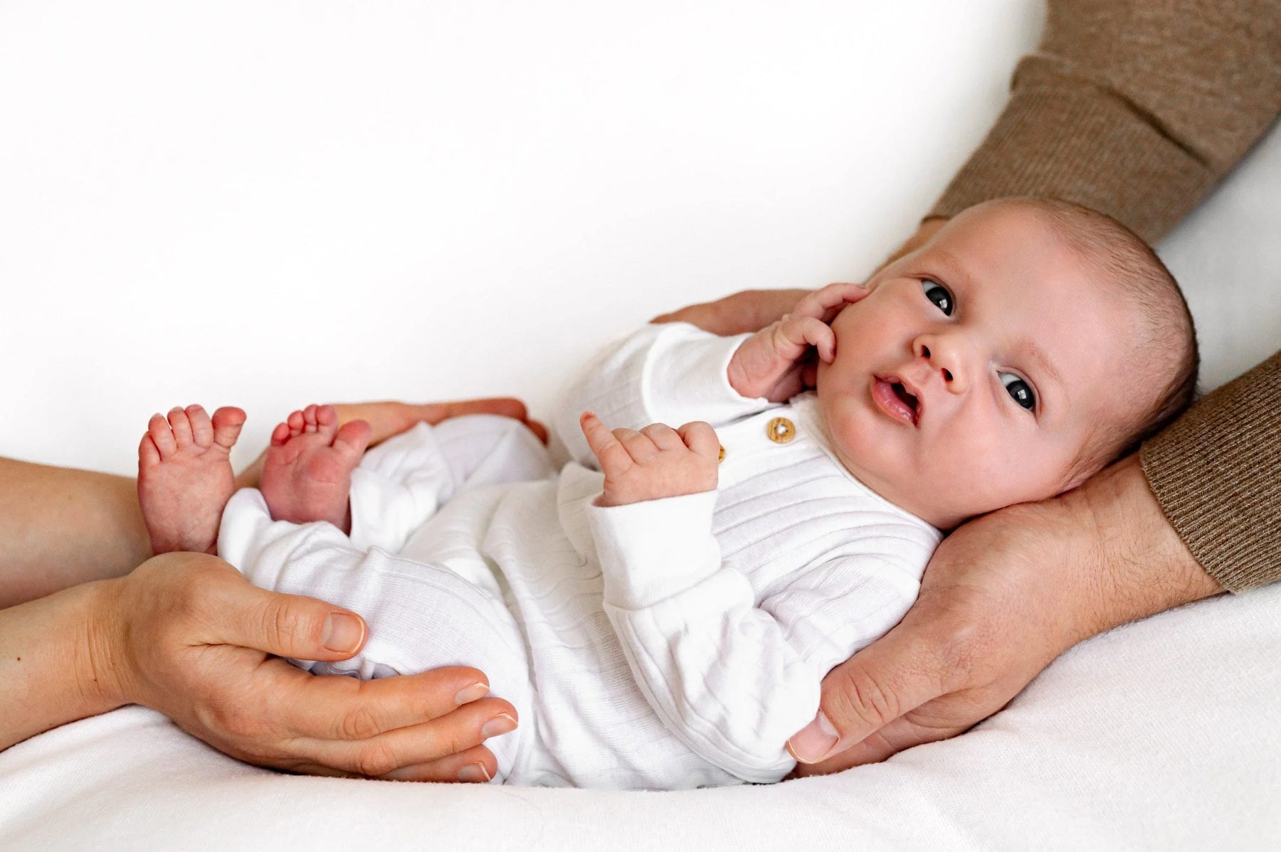 Ekologiska babyprodukter som nappflaskor, filtar och kläder upplagda på en säng.