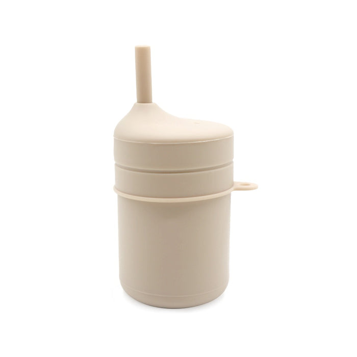 En beige cylindrisk TOS Silikon Pipmugg Sugrör från Toddlers Of Sweden, med en pip på toppen och ett handtag på sidan. Den minimalistiska designen har rena linjer och släta ytor, vilket gör den lämplig för barn. Denna BPA-fria kopp är perfekt för små händer och visas mot en vanlig vit bakgrund.