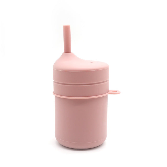 En TOS Silikon Pipmugg Sugrör från Toddlers Of Sweden i rosa silikon, med ett inbyggt sugrör och en rundad, spillsäker topp. Denna BPA-fria kopp har ett öglahandtag för enkel bäring och är speciellt designad för småbarn och småbarn. Bägaren står upprätt på en vit bakgrund.